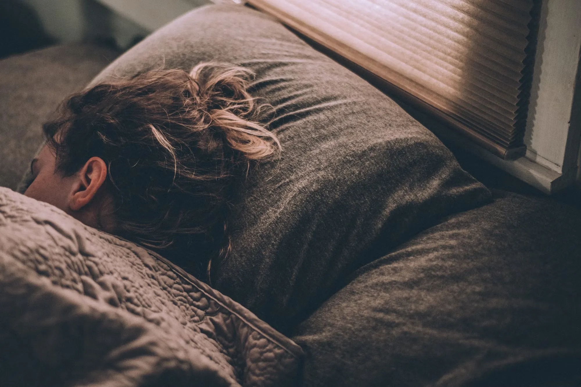 

A woman lying in bed, peacefully sleeping with a contented smile on her face.